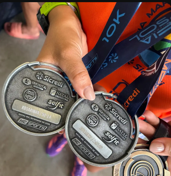 Atleta segurando medalhas com a marca Sicredi e gravação de nome e tempo